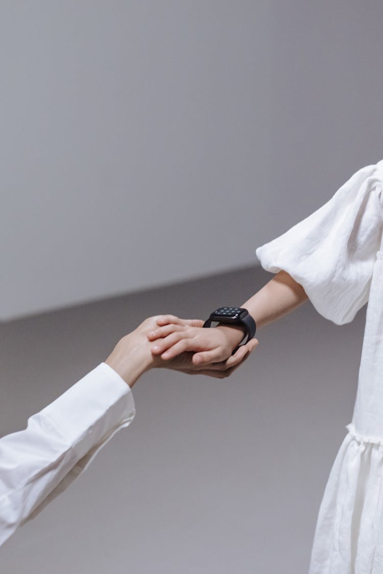 Mother Holding Hand Of Daughter With Smartwatch