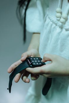 A young girl using a smartwatch showing a numeric keypad, highlighting technology interaction.