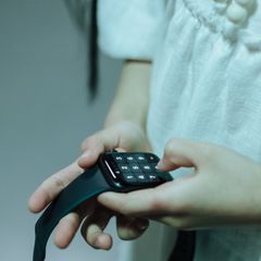 A child tapping the keypad on a dark smartwatch