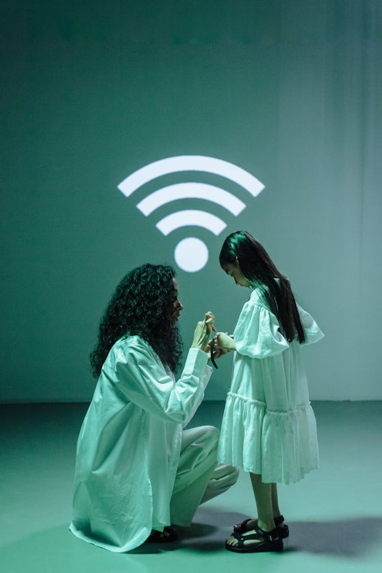 Woman In White Scrubs Connecting A Smartwatch Of A Girl To Wifi