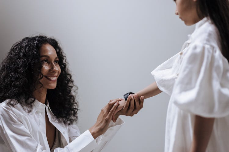 Mother Holding Hand Of Daughter With Smartwatch