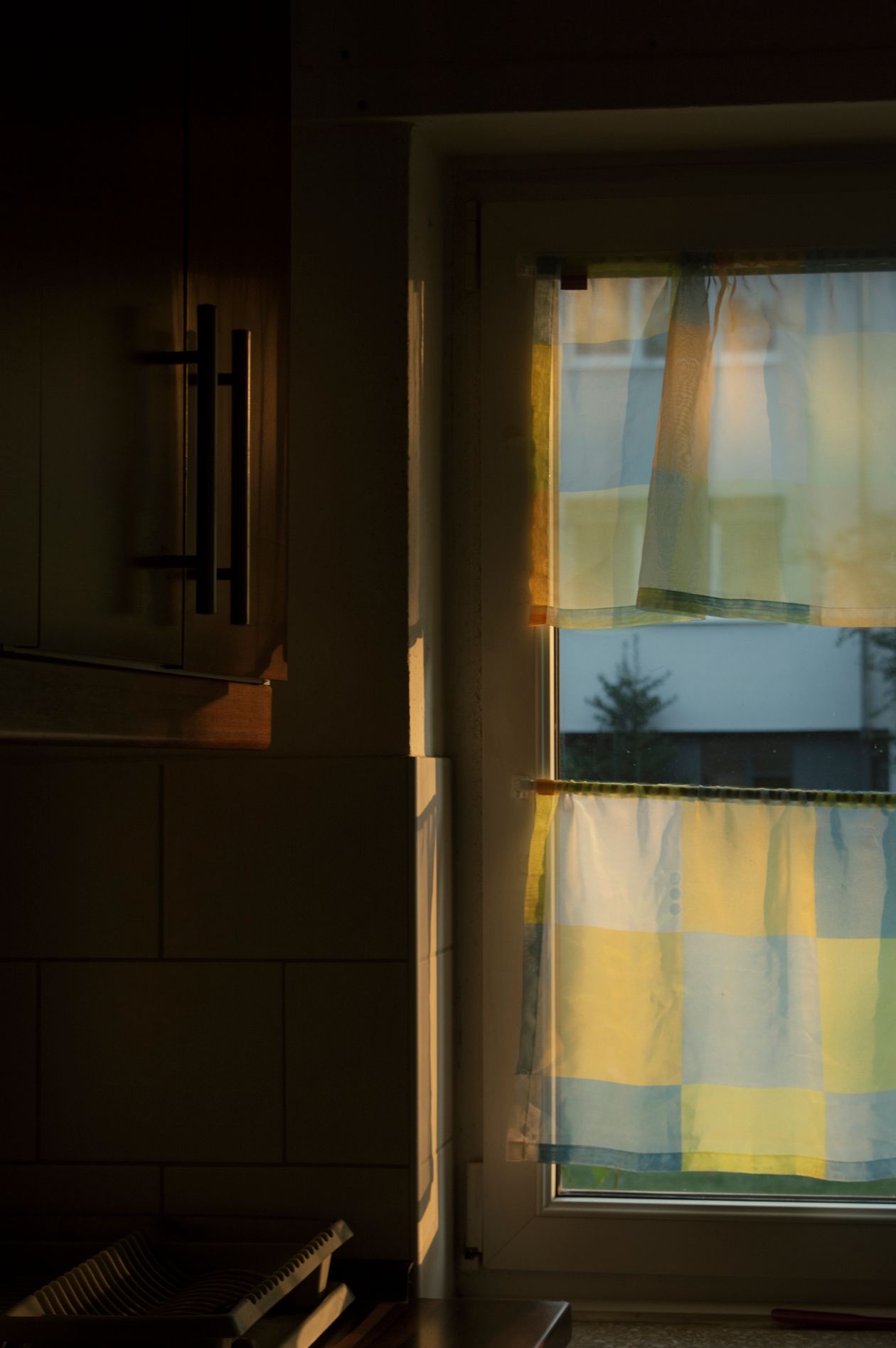 how to swap curtains for fall: a kitchen window with checkered curtains at sunset