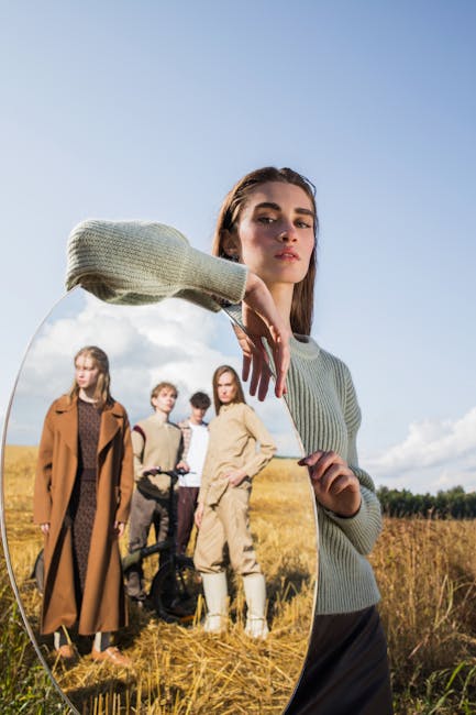 Fashionable young adults posing with mirror reflection in a scenic field outdoors.