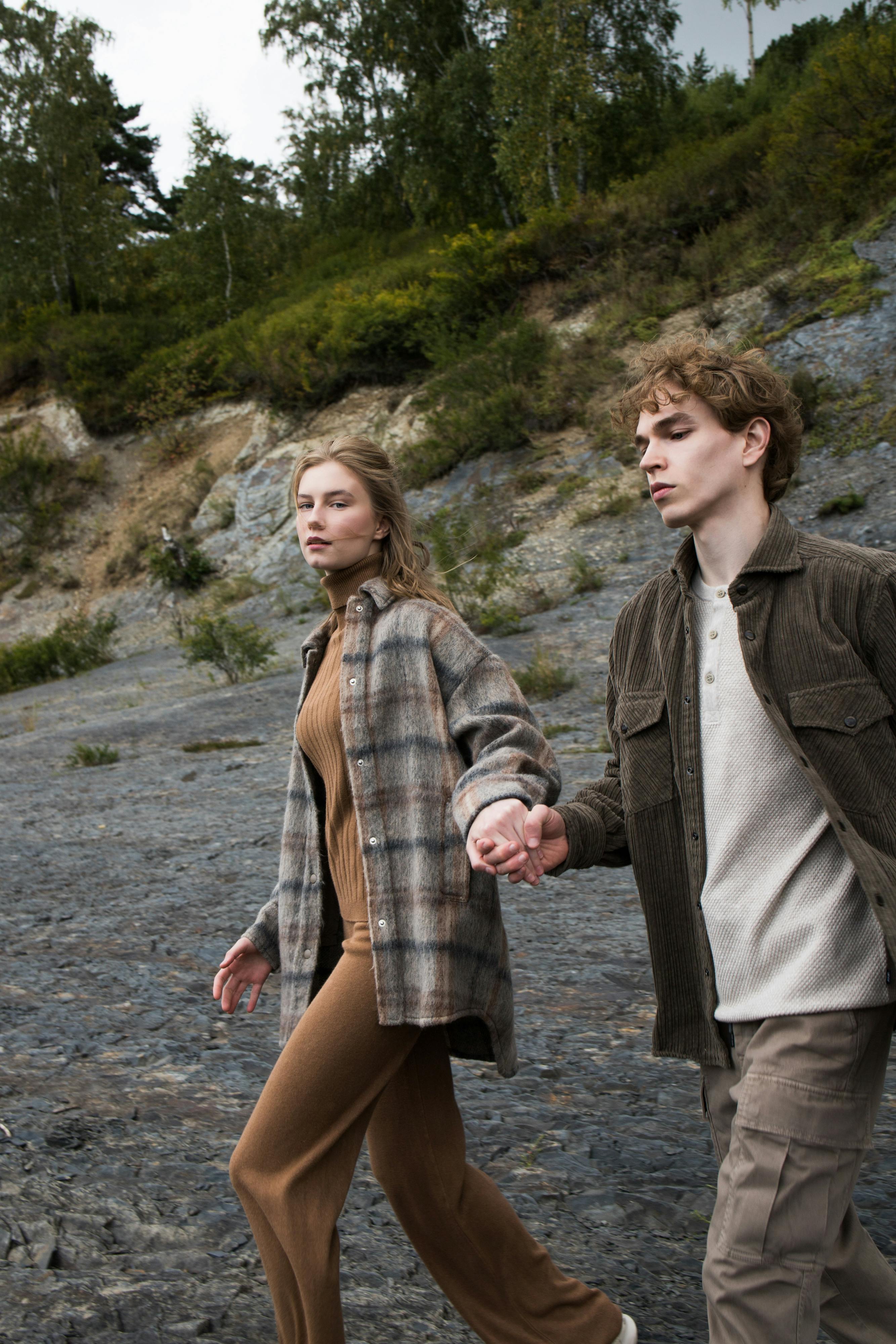 A young couple walks hand in hand across a rocky outdoor terrain, exemplifying connection and exploration.