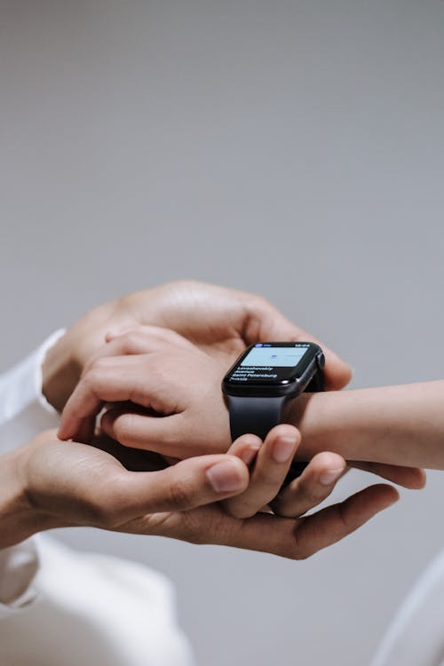 Hand holding kid hand with smartwatch