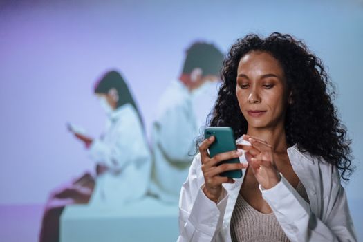 Woman in lab coat using smartphone