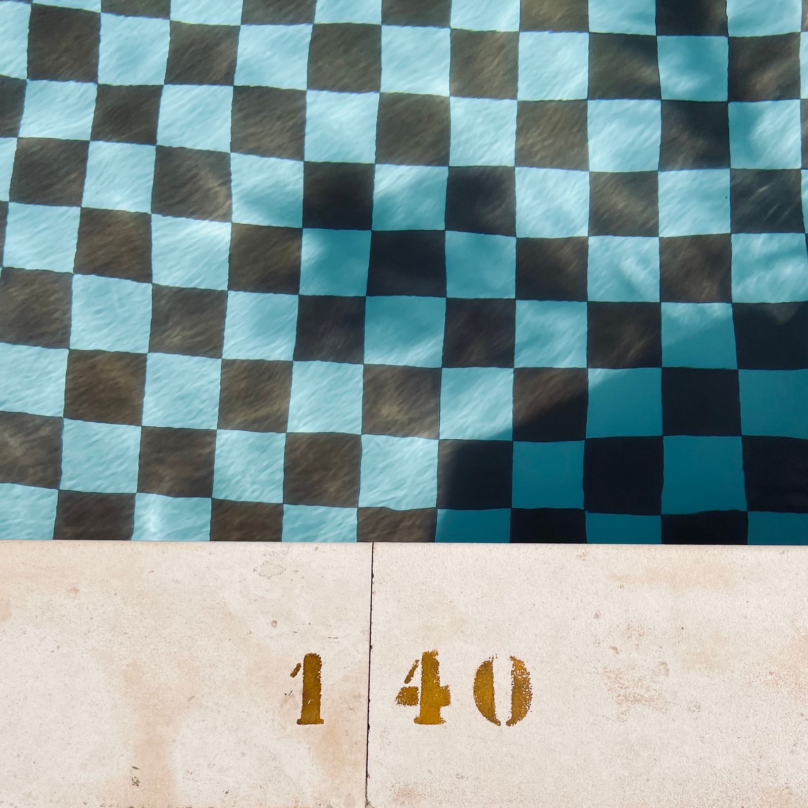 Black and white checked tiles under water beside a painted depth marker