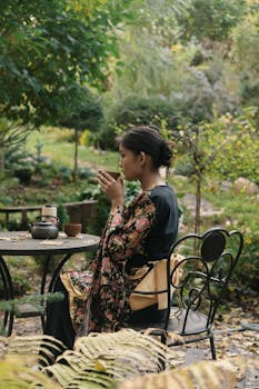 A woman peacefully enjoying tea in a garden while wearing a kimono, with nature's beauty surrounding her.
