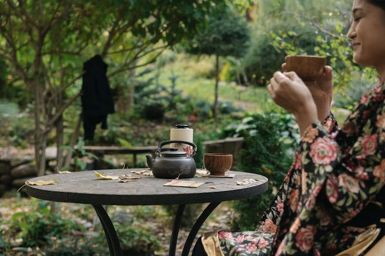 A Woman In A Floral Kimono Drinking Tea In A Garden