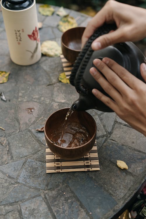 Free A Person Pouring Tea in a Wooden Bowl Stock Photo