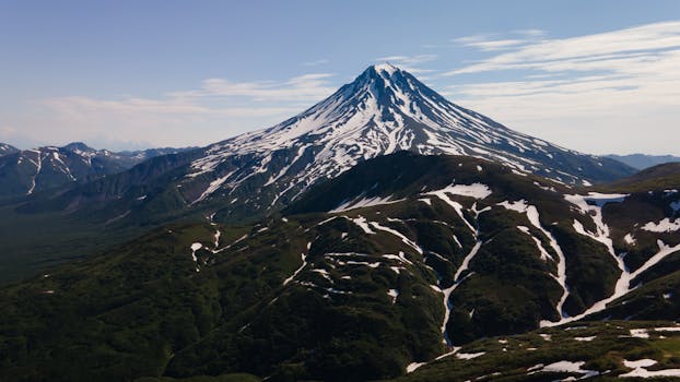 A breathtaking view of a snow-capped volcano in Kamchatka, showcasing rugged terrain and natural beauty.