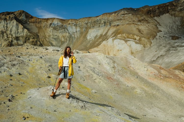 Woman In Yellow Jacket And Denim Shorts Standing On The Rocky Mountain