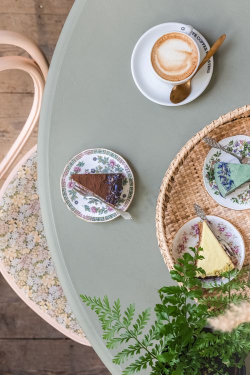 Free Top view of a cozy table setting with coffee and assorted cake slices on floral plates. Stock Photo