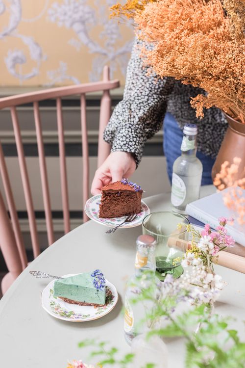 Free A hand serving chocolate cake in a cozy indoor setting with floral accents. Stock Photo