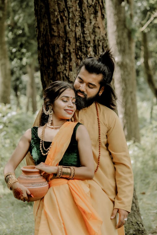 Adult Hindu couple flirting under big tree in forest
