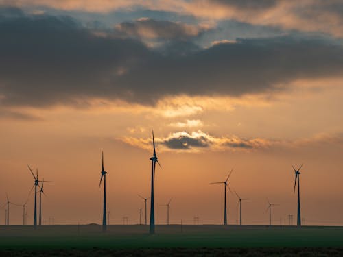 Wind Turbines Under a Cloudy Sky during Sunset