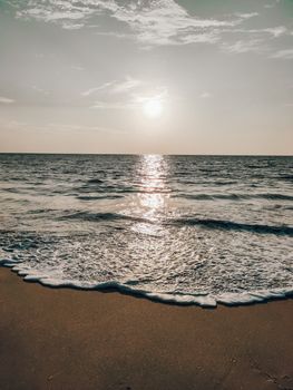 Peaceful sunrise at the beach with waves gently lapping the shore, capturing serene ocean scenery.