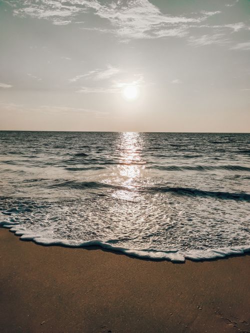 Free Peaceful sunrise at the beach with waves gently lapping the shore, capturing serene ocean scenery. Stock Photo
