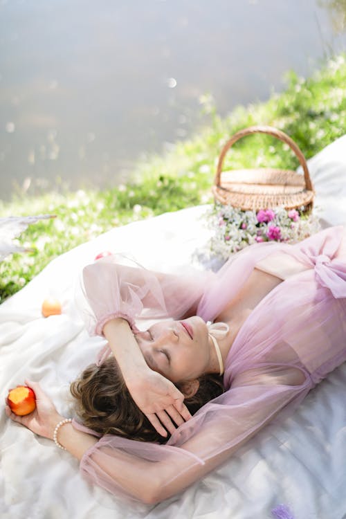 Free A Woman Sleeping while Lying on the Blanket Beside the River Stock Photo