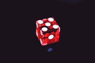 特写镜头中，黑色背景上的红色透明骰子带有鲜艳的白点，形成高对比度的视觉效果