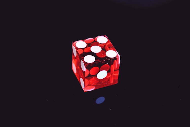 Red Translucent Die On Top Of Black Surface