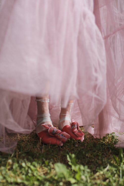 A Woman in Pink Long Dress and Pink Shoes Standing on Green Grass