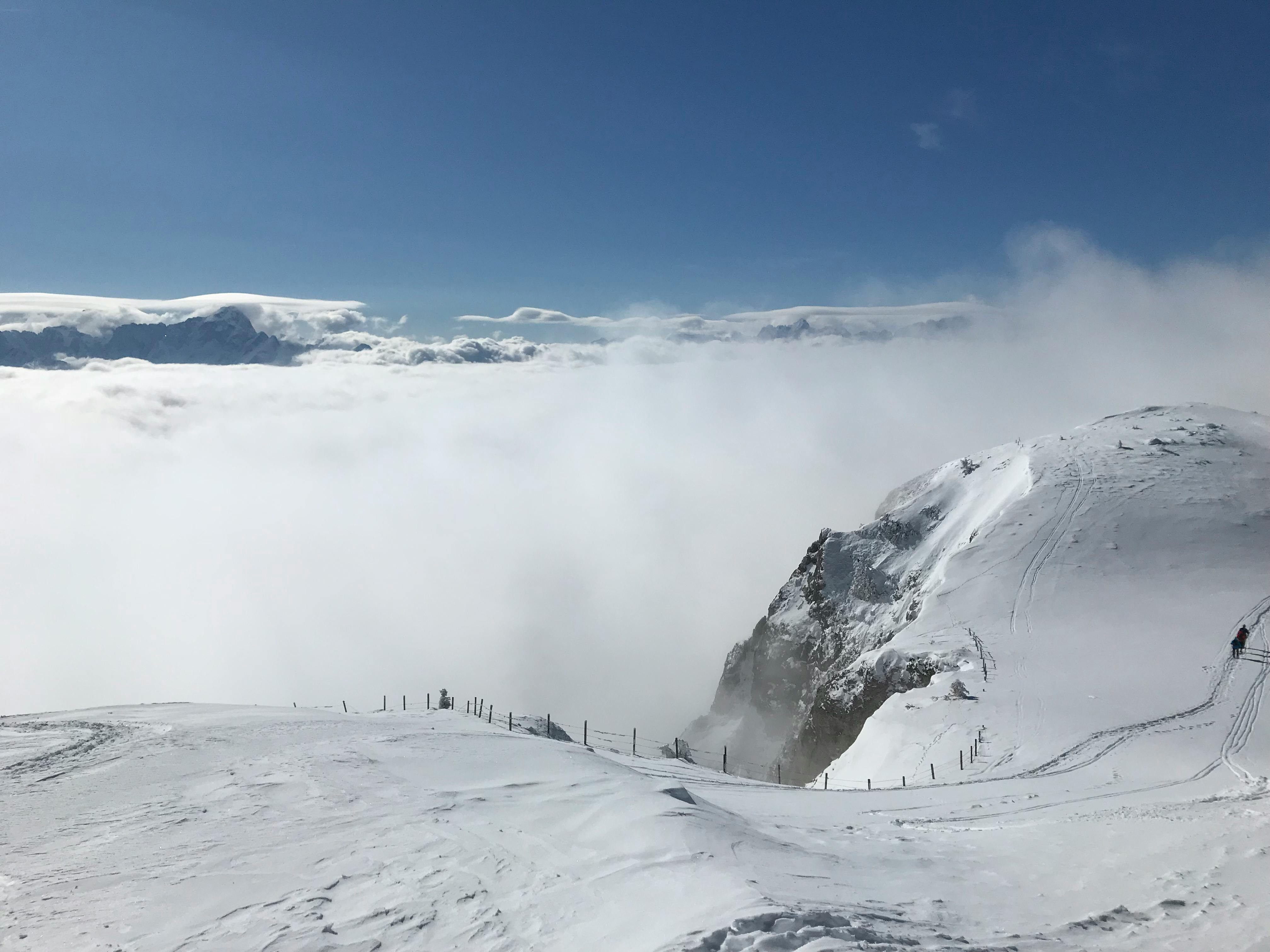云层包裹着冰雪覆盖的山峰，视野开阔，非常适合冬季冒险