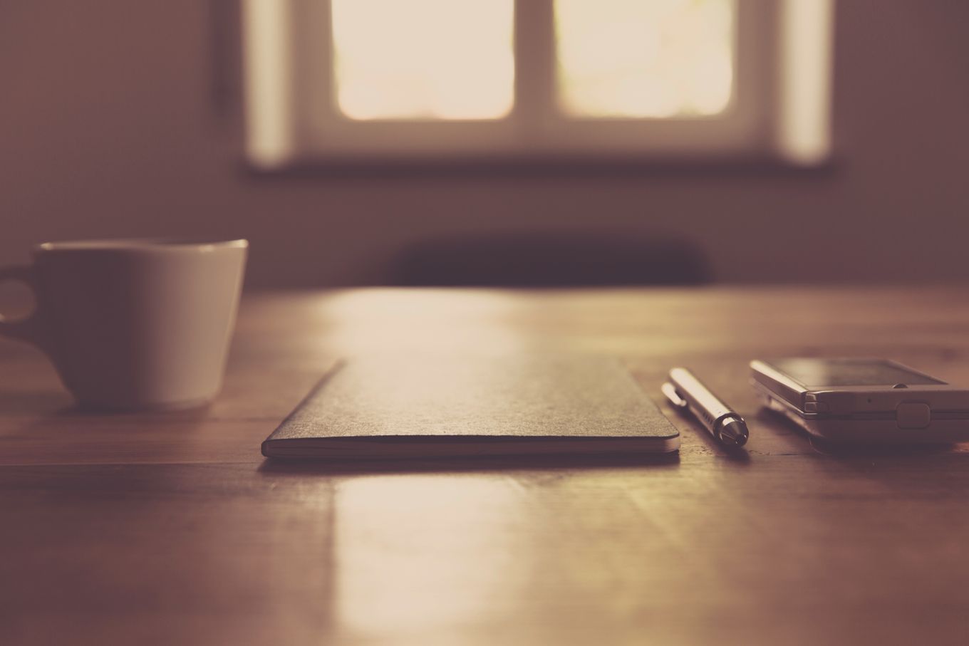 A quiet table by a bright window with a notebook, pen and cup — photo by Markus Spiske on Pexels