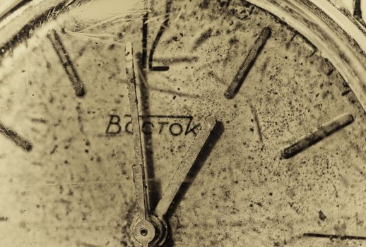 Close-up of an old Vostok clock face in sepia, highlighting its vintage appeal and rustic charm.