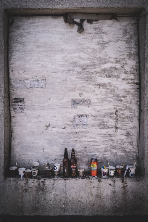Free A gritty urban scene featuring abandoned bottles and disposable cups on a ledge. Stock Photo