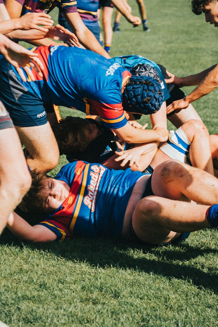 Man In Blue And Red Jersey Shirt Lying On Green Grass Field