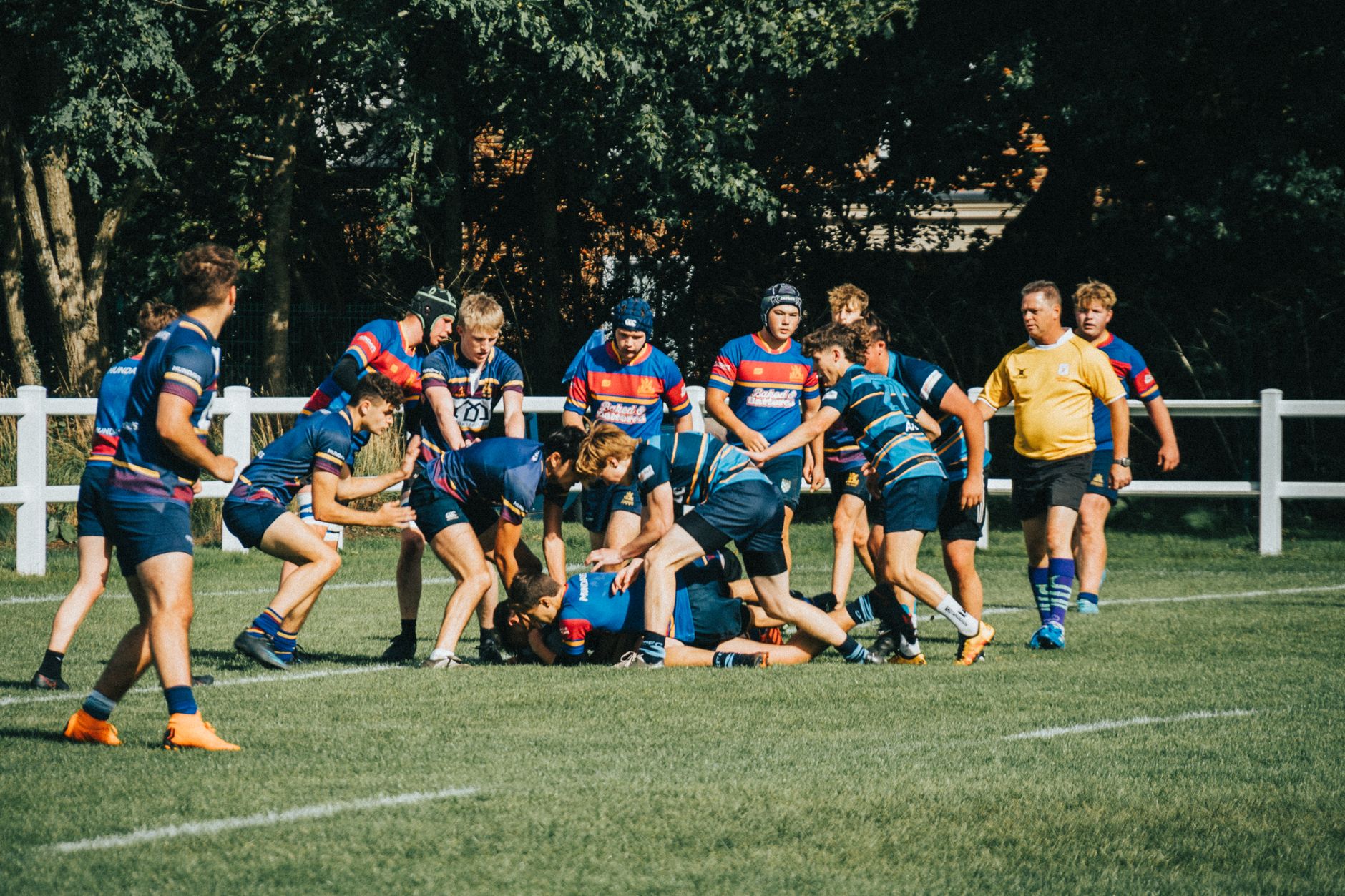 Rugby players engage in a dynamic game on a sunny outdoor field, showcasing teamwork and strategy.