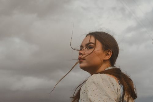 Free Captivating portrait of a woman with flowing hair against an overcast sky, evoking a contemplative mood. Stock Photo