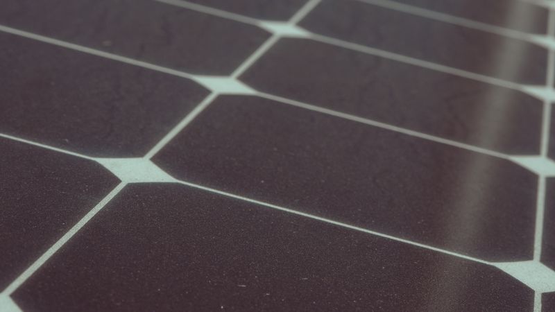 black solar collector panels mounted on a south-facing roof above a backyard pool