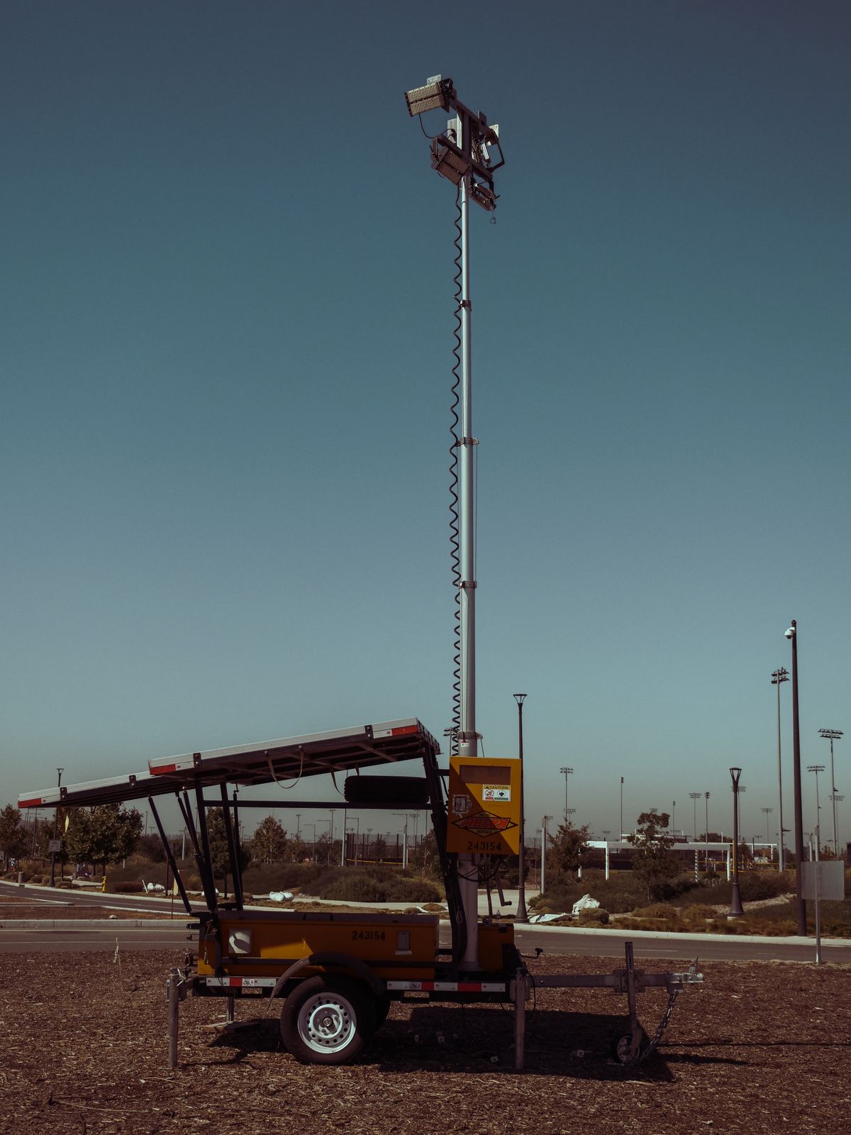 Trailer-mounted lighting mast raised on open ground, showing the towable chassis, outriggers and mast assembly