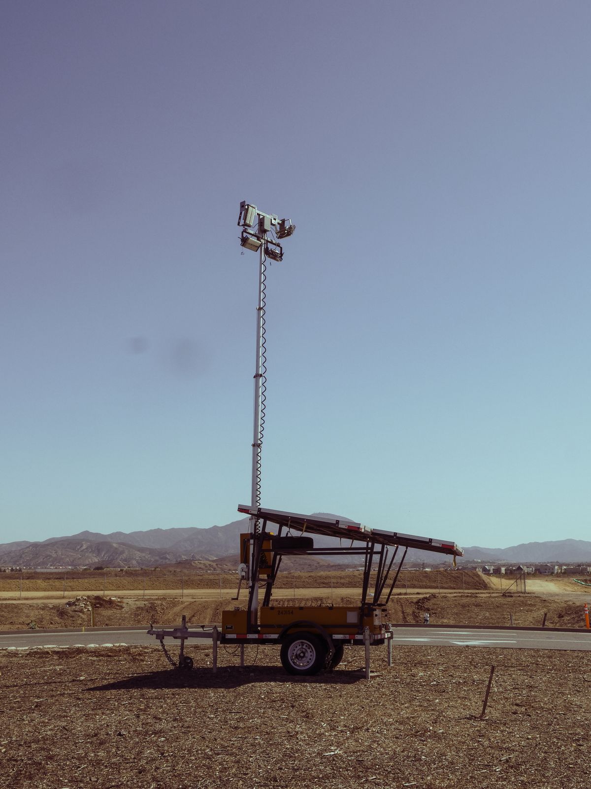 Mobile light tower with telescopic mast raised to full height on open ground, showing how mast height creates area coverage