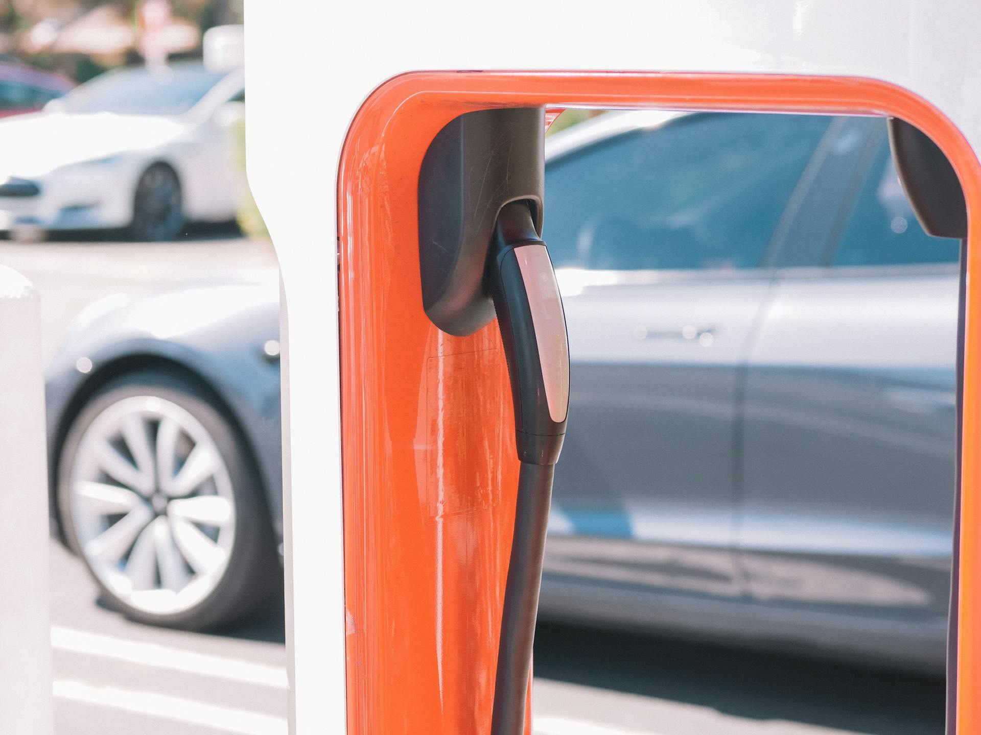 Close-up of an electric vehicle charger with a car in the background, highlighting clean energy.