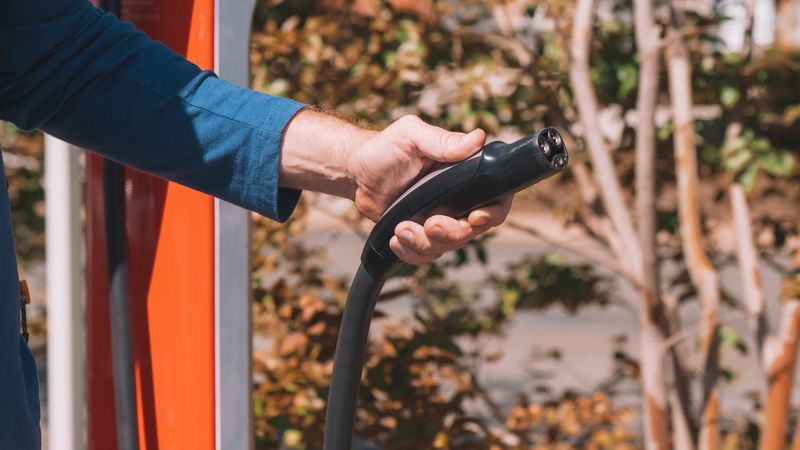 portable electric vehicle charger plugged into an outdoor weather-resistant receptacle box with a closed cover