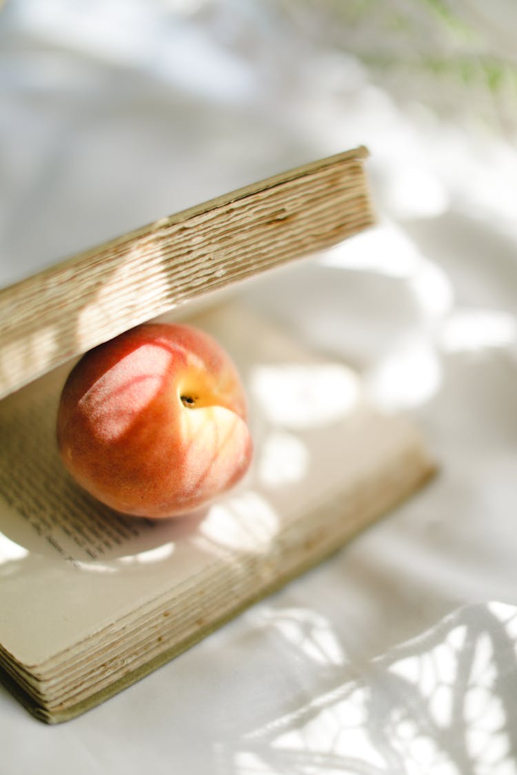 A Close-Up Shot Of A Peach On A Book