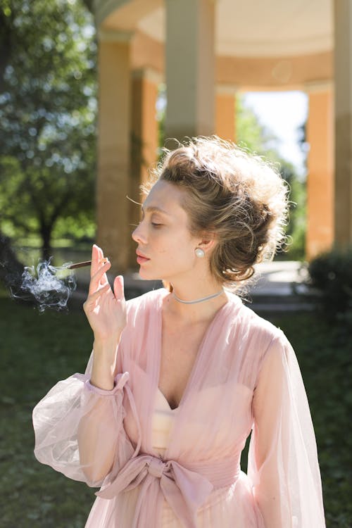 Woman in Pink Dress Smoking a Cigarette