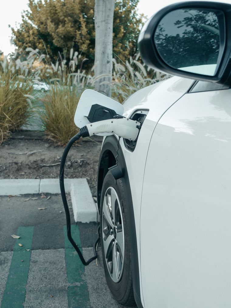 Coche eléctrico enchufado a un punto de carga en una plaza de aparcamiento