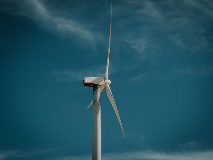 Wind turbine against a clear blue sky, symbolizing renewable energy.