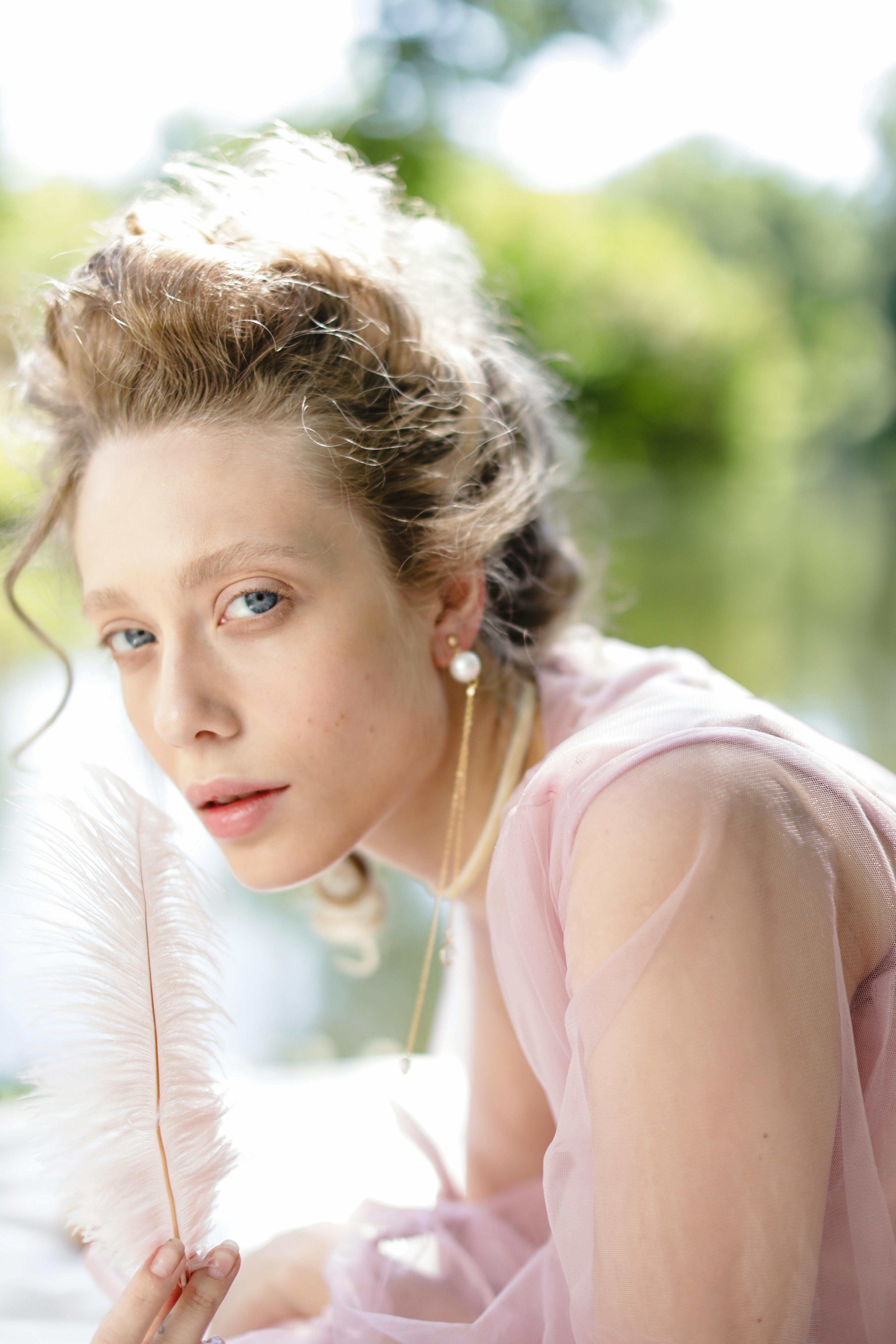 Elegant portrait of a woman in soft lighting holding a feather. Perfect for beauty and fashion themes.