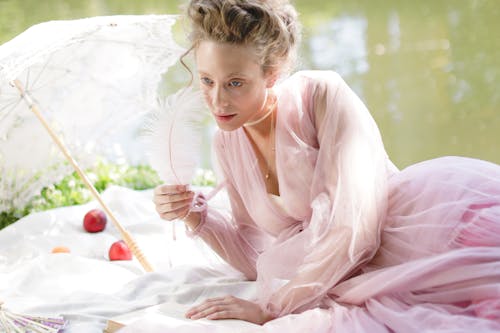 A Woman in a Pink Dress Holding a White Feather