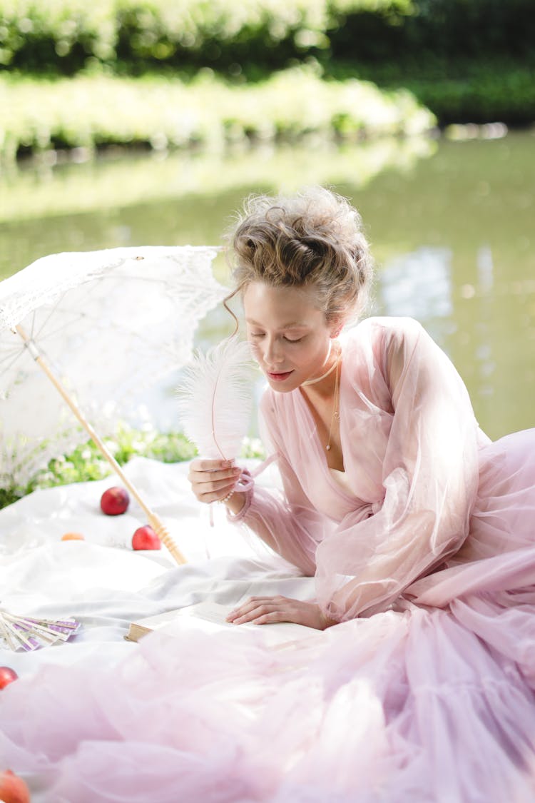 Beautiful Woman Holding A Feather While Reading A Book