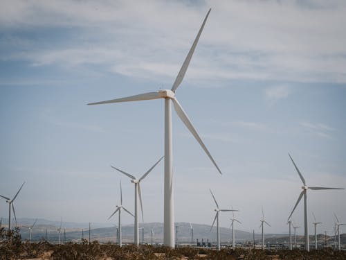 White Wind Turbines on Brown Grass Field Under the Sky