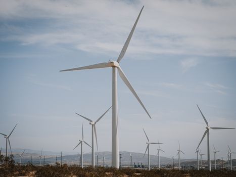 White Wind Turbine on Brown Grass Field Under Blue Sky