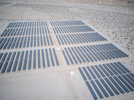 Expansive aerial view of solar panels in a desert, showcasing renewable energy technology.
