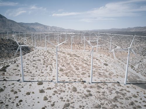 Free Aerial view of a wind farm with turbines on a vast desert landscape under a clear sky. Stock Photo