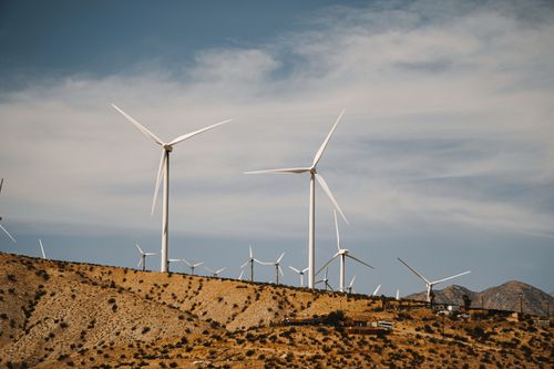 Free Wind turbines on a sunny desert hillside with clear skies, showcasing renewable energy use. Stock Photo